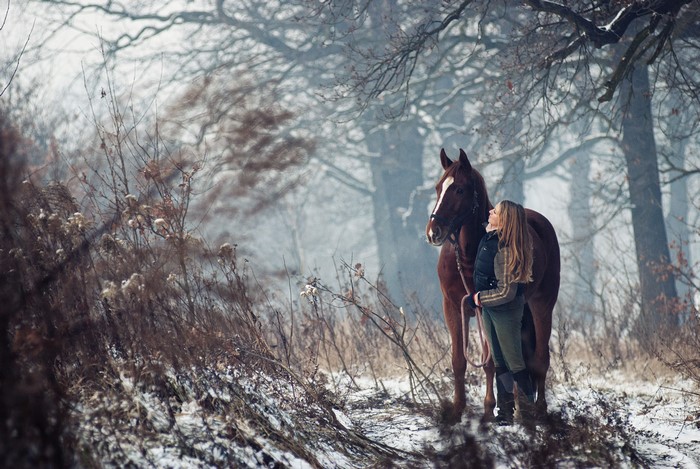 Woman and horse in a snowy forest