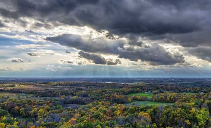 Autumn forest landscape with sunbeams through clouds in Wisconsin
