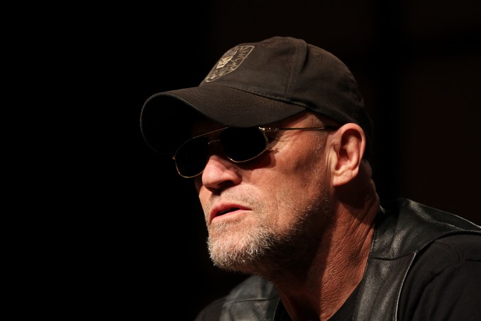 Michael Rooker wearing a baseball cap and sunglasses
