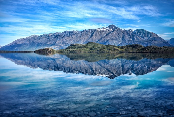 Mountains reflected in a clear lake under a blue sky
