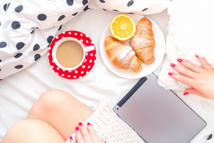 Breakfast in bed with coffee, croissants, and tablet