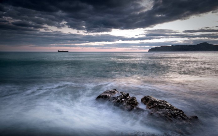Ship on the horizon with stormy clouds over the sea