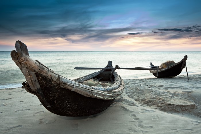 Boats on a sandy beach at sunset