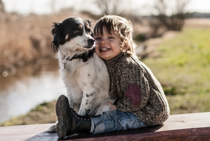 A boy and his dog sitting on a bench