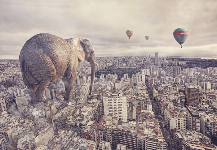 Giant elephant over city with hot air balloons