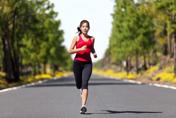 Woman running on a tree-lined road