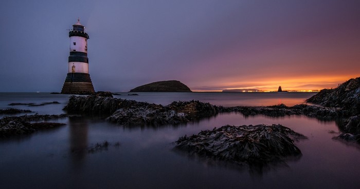 Penmon Lighthouse at dusk with rocky shore