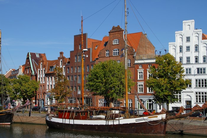 Sailing ships docked in Lubeck, Germany harbor with historic buildings