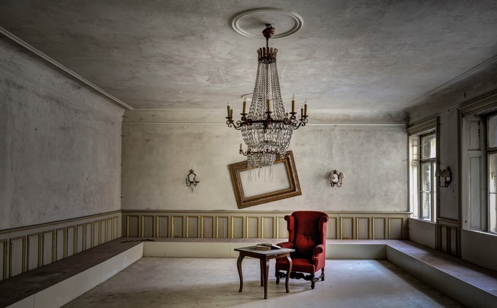 Abandoned room with chandelier, armchair, and table
