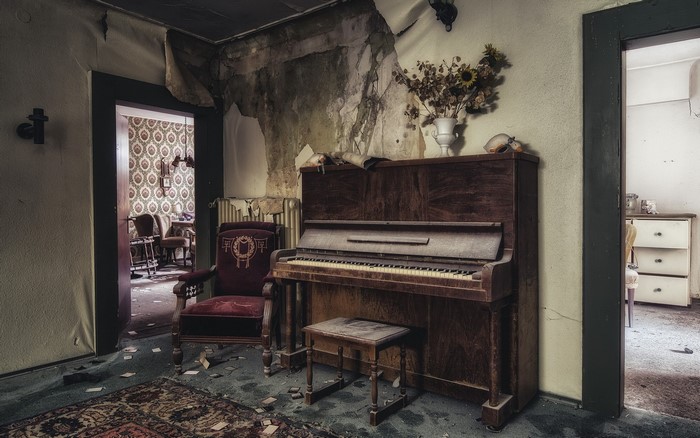 Abandoned room with a piano and armchair