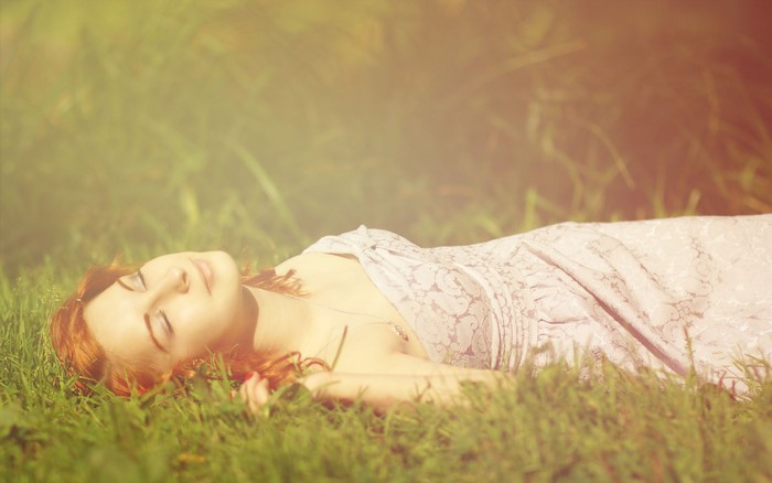 Redhead girl sleeping on grass