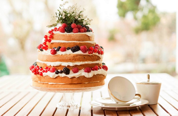 Naked cake with berries and flowers on a table