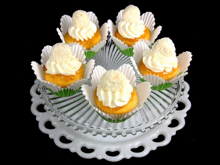 Mini cakes with frosting and coconut on a cake stand