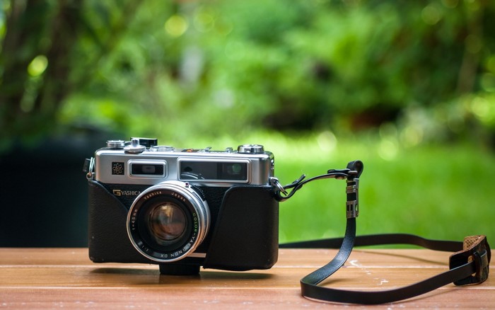 Yashica retro camera with strap on wooden table