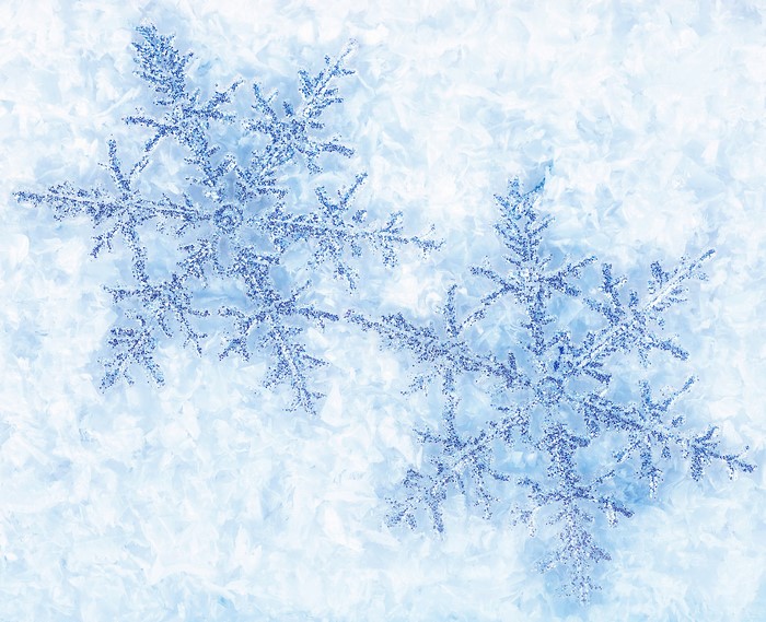 Close-up of two blue glitter snowflakes on ice