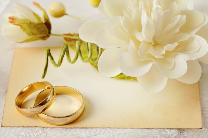 Two gold wedding rings on a card with flowers