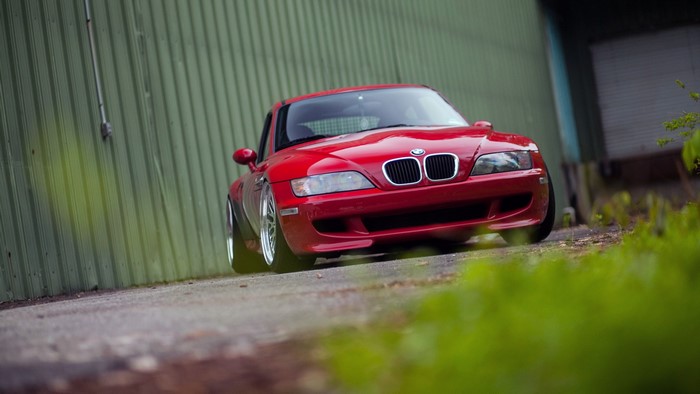 Red BMW Z3 Coupe parked next to a green building