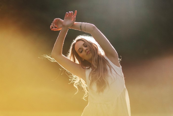 Woman with arms raised in sunlight