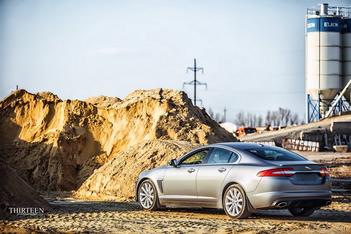 Silver Jaguar XF parked near sand piles