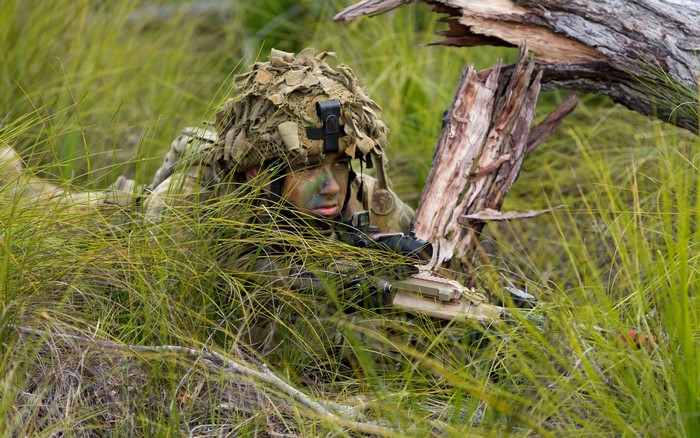 Soldier in camouflage hiding in tall grass