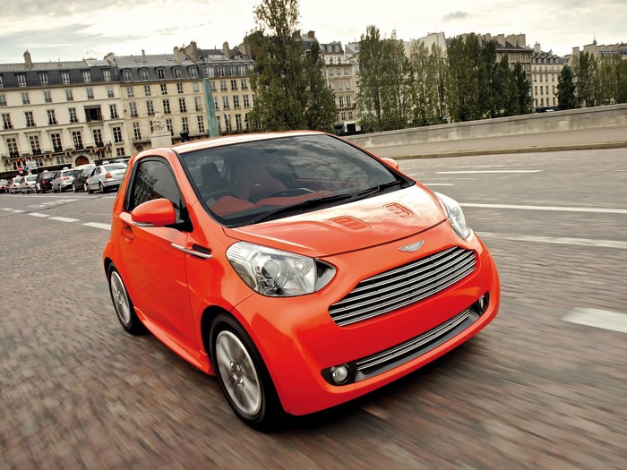Orange Aston Martin Cygnet driving on a street