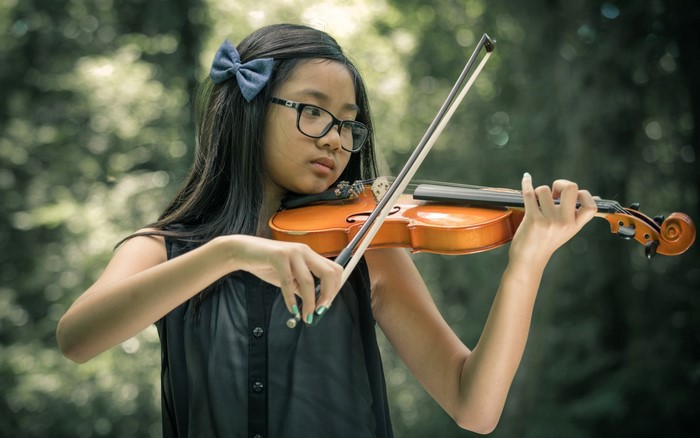 Young Asian girl playing the violin outdoors