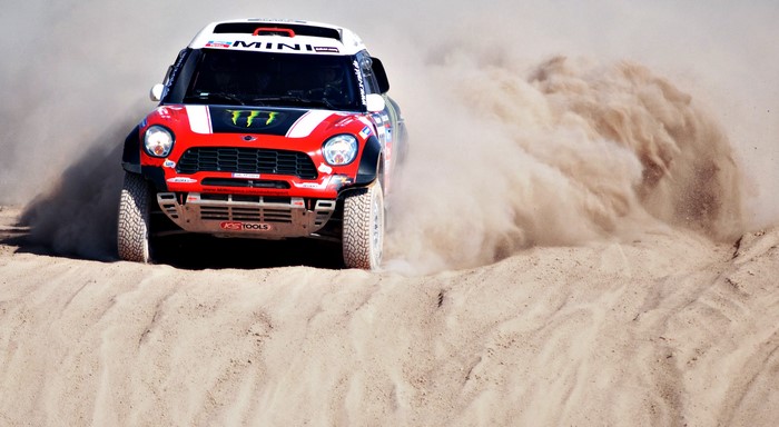 Mini Cooper Dakar Rally car kicking up sand