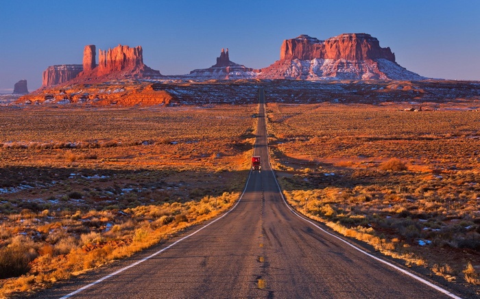 Monument Valley road with a truck at sunrise