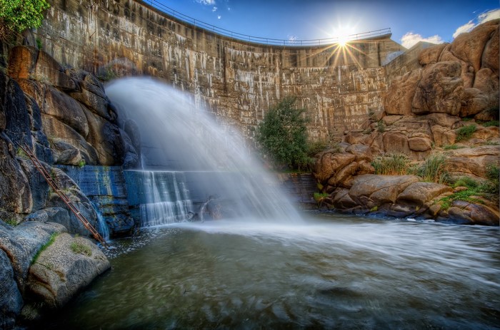 Dam with water flowing and sun rays