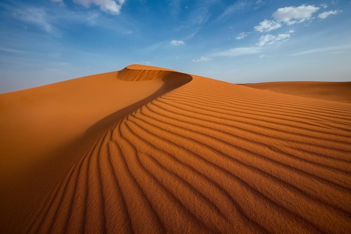 Desert sand dunes under a blue sky