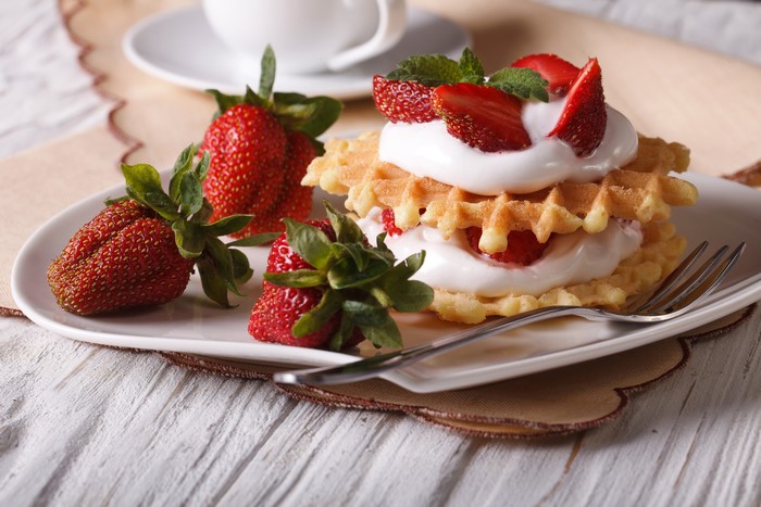 Waffles with whipped cream and strawberries on a plate