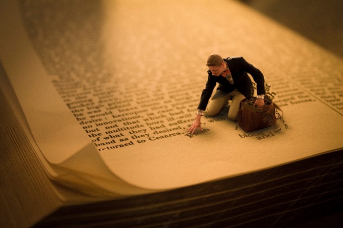 Man kneeling on a book page