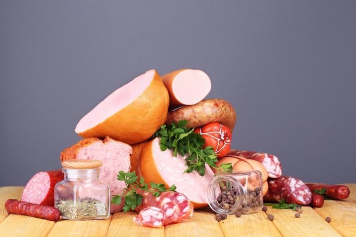 Meat products, sausages, spices, and jars on a wooden table