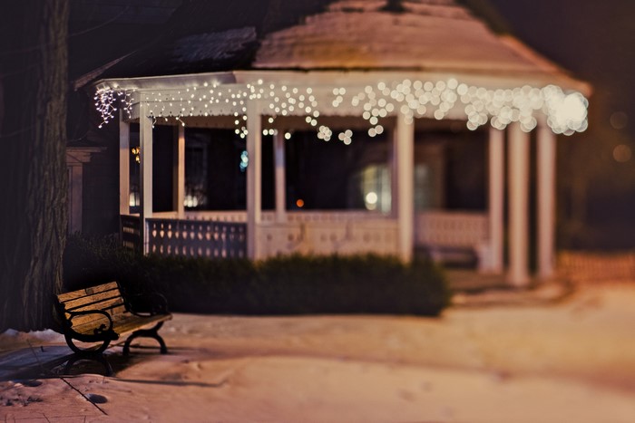 Gazebo with fairy lights and bench at night