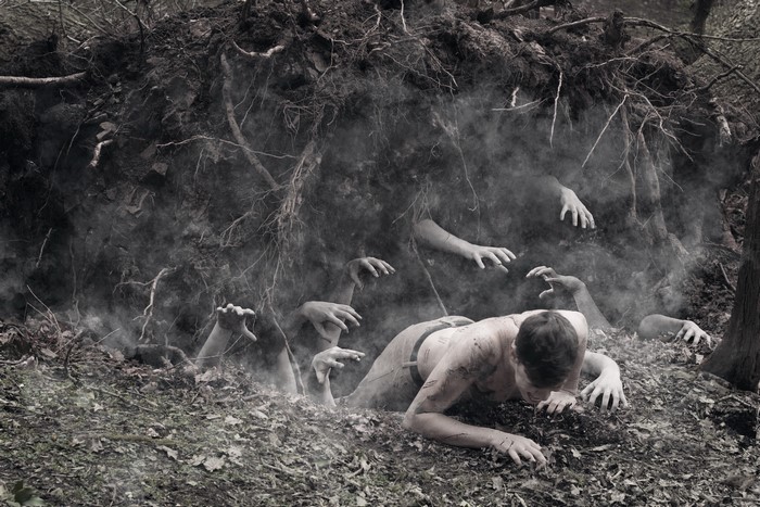 Man crawling from earth with hands emerging