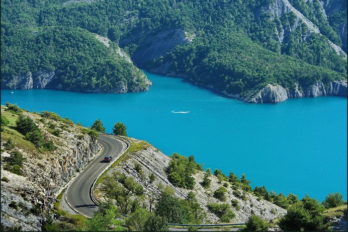 Winding mountain road overlooking a turquoise lake in France