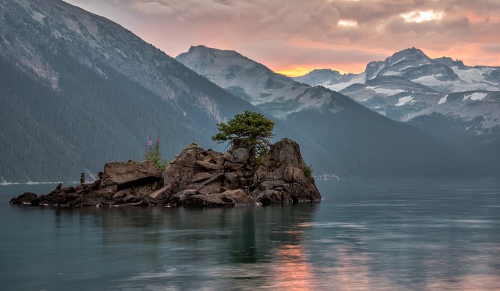 Island with tree in lake at sunset with mountains