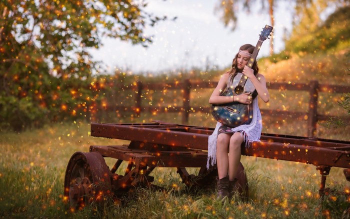 Girl with guitar sitting on a rusty trailer