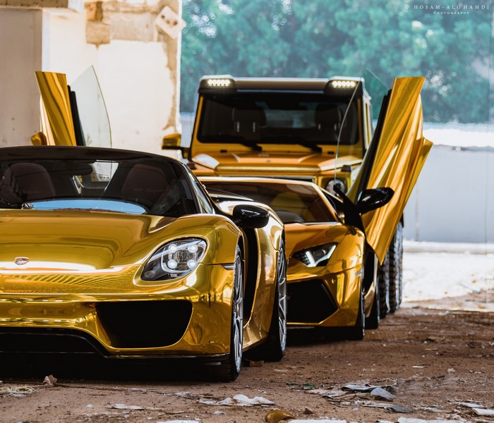 Three gold luxury cars: Porsche, Lamborghini, and Mercedes-Benz G63 AMG 6x6