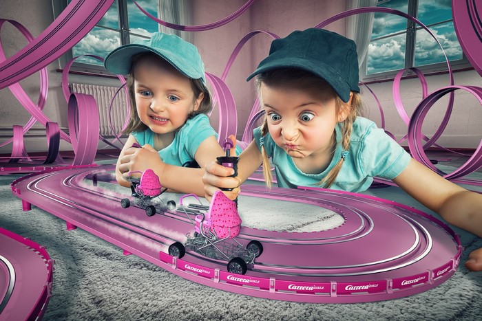 Two girls playing with a Carrera race track