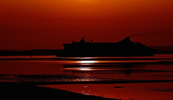 Cruise liner silhouetted against a red sunset over the sea