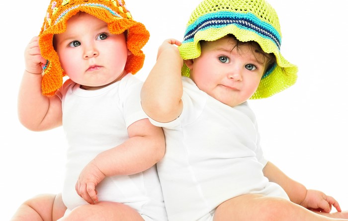 Two infants wearing colorful hats
