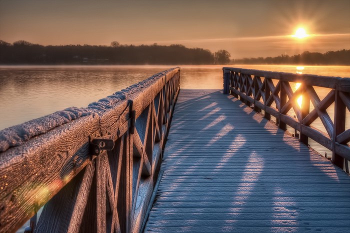Wooden pier on a frozen lake at sunrise