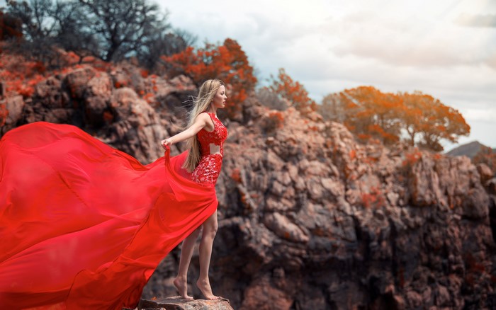 Blonde girl in red dress on a crag
