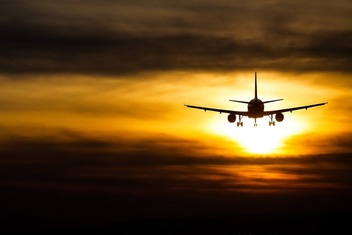 Airplane flying against a sunset sky