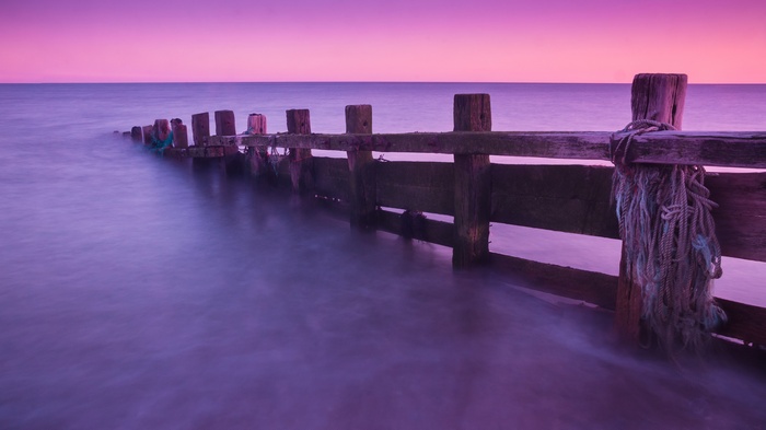 Wooden groyne in the sea at sunset