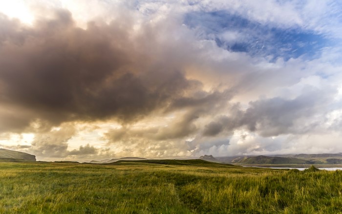 Grassy fields under dramatic clouds in Iceland