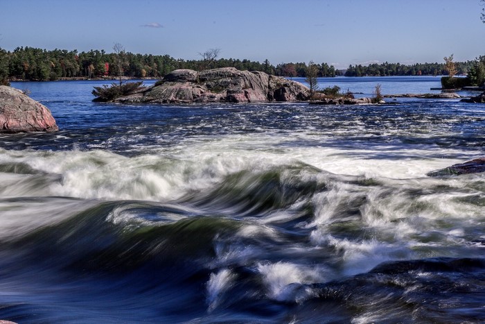 Fast-flowing river with rocky islands and trees