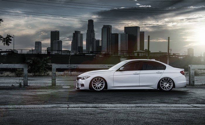 White BMW 328i F30 parked with city skyline