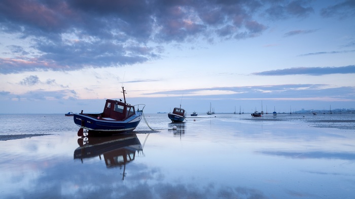 Boats on a calm sea at dusk with reflections